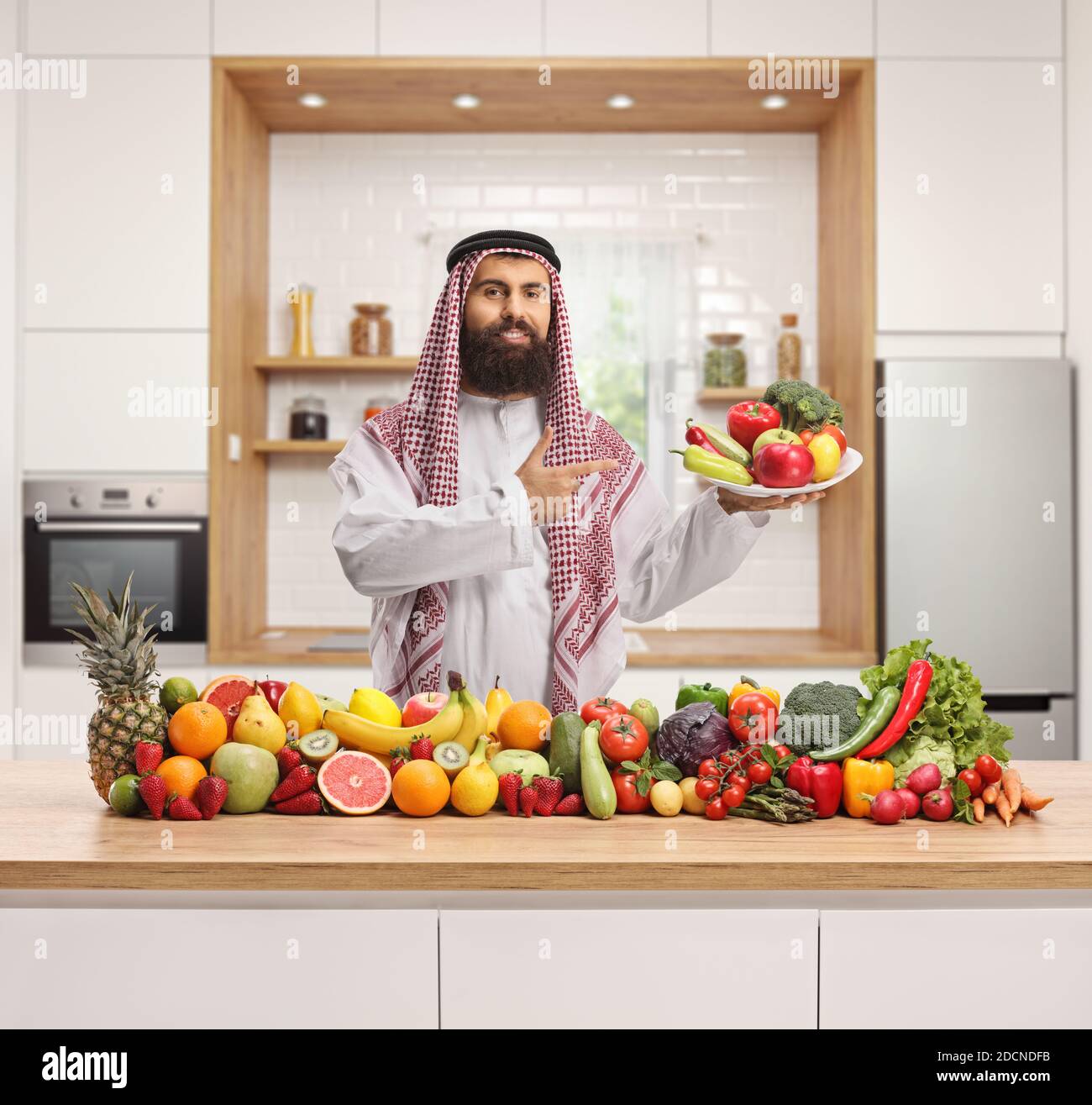 Saudi-arabischen Mann hält einen Teller mit frischen Früchten und Gemüse in einer modernen Küche Stockfoto