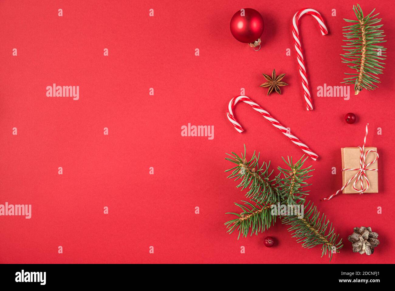 Weihnachts- oder Neujahrsgestaltung aus Tannenzweigen, Geschenkschachteln und Weihnachtsdekorationen auf rotem Hintergrund. Flachlage. Draufsicht mit Kopierraum Stockfoto