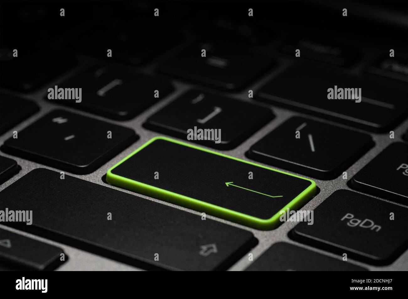 Grüne ENTER-Taste auf der Laptop-Tastatur im Dunkeln. Selektiver Fokus. Stockfoto