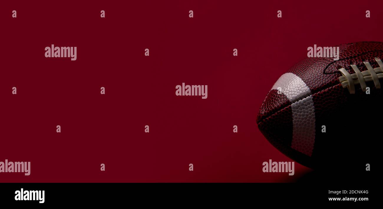 American Football Ball Nahaufnahme auf rotem Hintergrund. Spot Team Konzept Stockfoto
