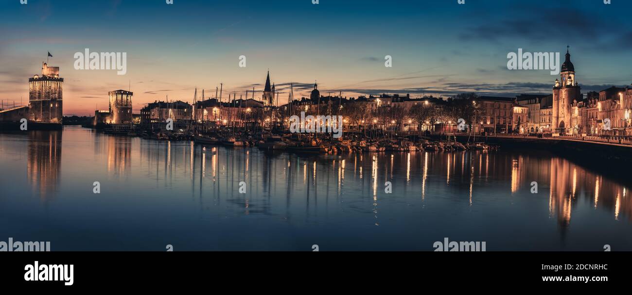 Panoramablick auf den alten Hafen von La Rochelle bei der blauen Stunde mit seinen berühmten alten Türmen Stockfoto