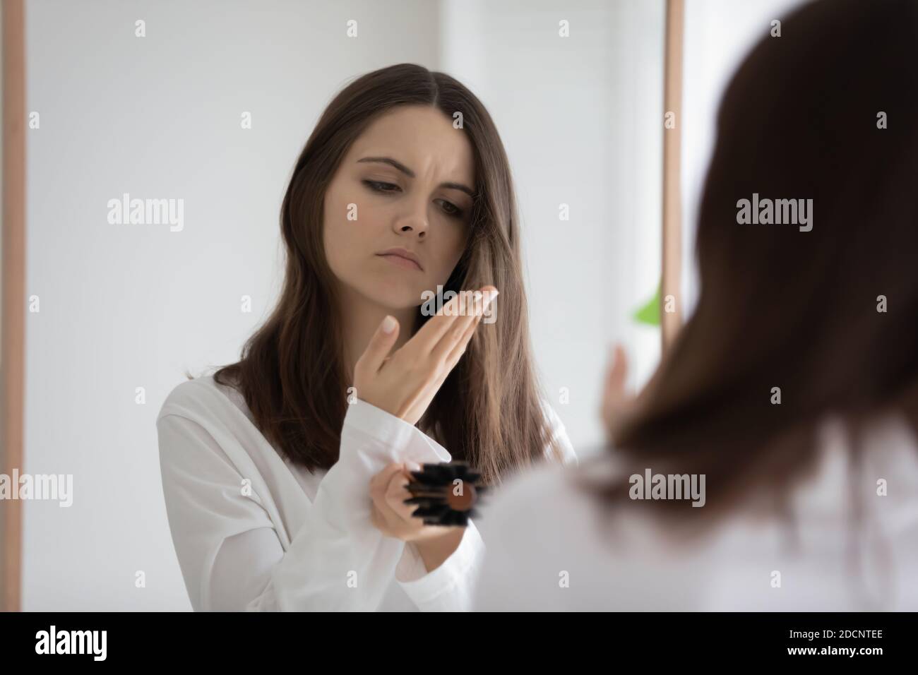 Verärgert Frau im Badezimmer stehend Blick auf ihr schwaches Haar Stockfoto