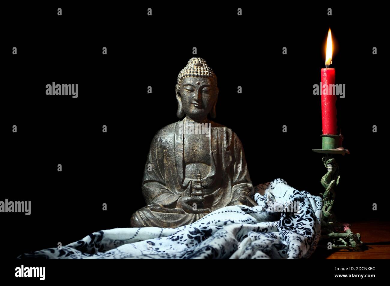 Meditierender Buddha neben einer brennenden Kerze. Philosophie oder Religion. Stockfoto