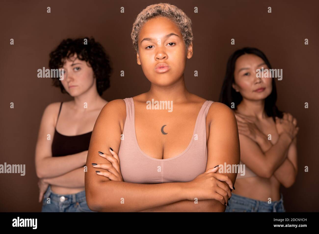 Junge seriöse blonde Mixed-Race-Frau vor zwei stehen Andere Frauen Stockfoto