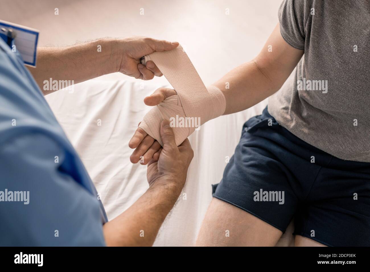 Hände des Arztes, die Handfläche und Handgelenk des kranken Patienten einwickeln Mit flexibler Bandage Stockfoto