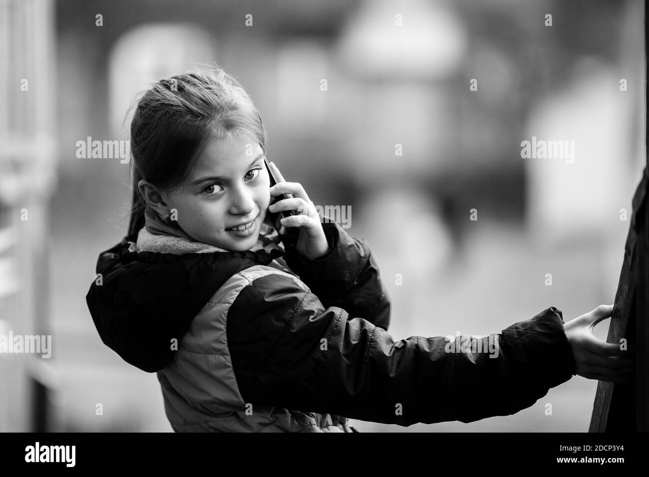 Kleines Mädchen Porträt, im Gespräch auf Handy, im Freien. Schwarzweiß-Fotografie. Stockfoto