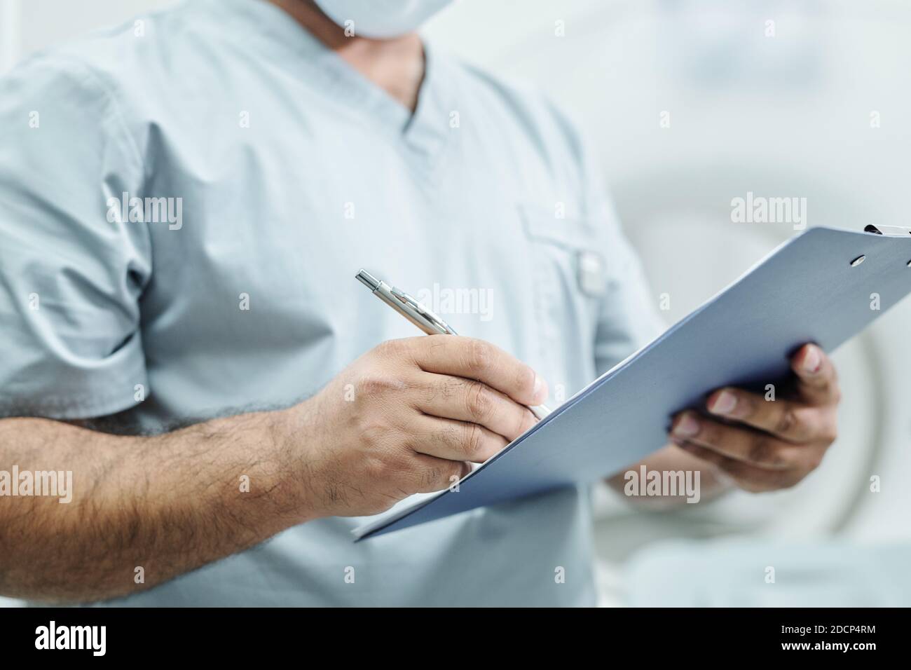 Hände von reifen Mischrasse männlichen Arzt in Uniform Notizen machen Im Dokument Stockfoto