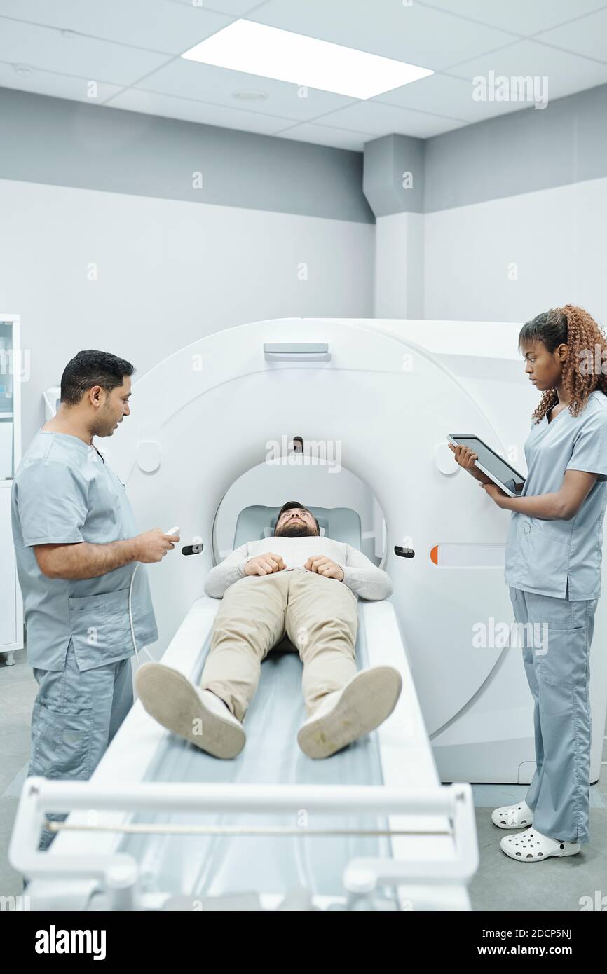 Junge Assistentin in Uniform und Arzt auf beiden Seiten Lange Couchette Stockfoto