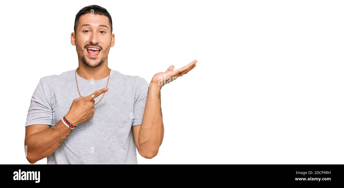 Schöner Mann mit Tattoos im 90s-Stil erstaunt und lächelnd auf die Kamera, während mit der Hand und mit dem Finger zeigen. Stockfoto