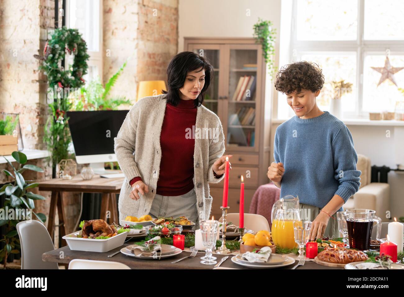 Zwei Frauen diskutieren, wo man dieses oder jenes hausgemachte setzen Essen am servierten Tisch Stockfoto