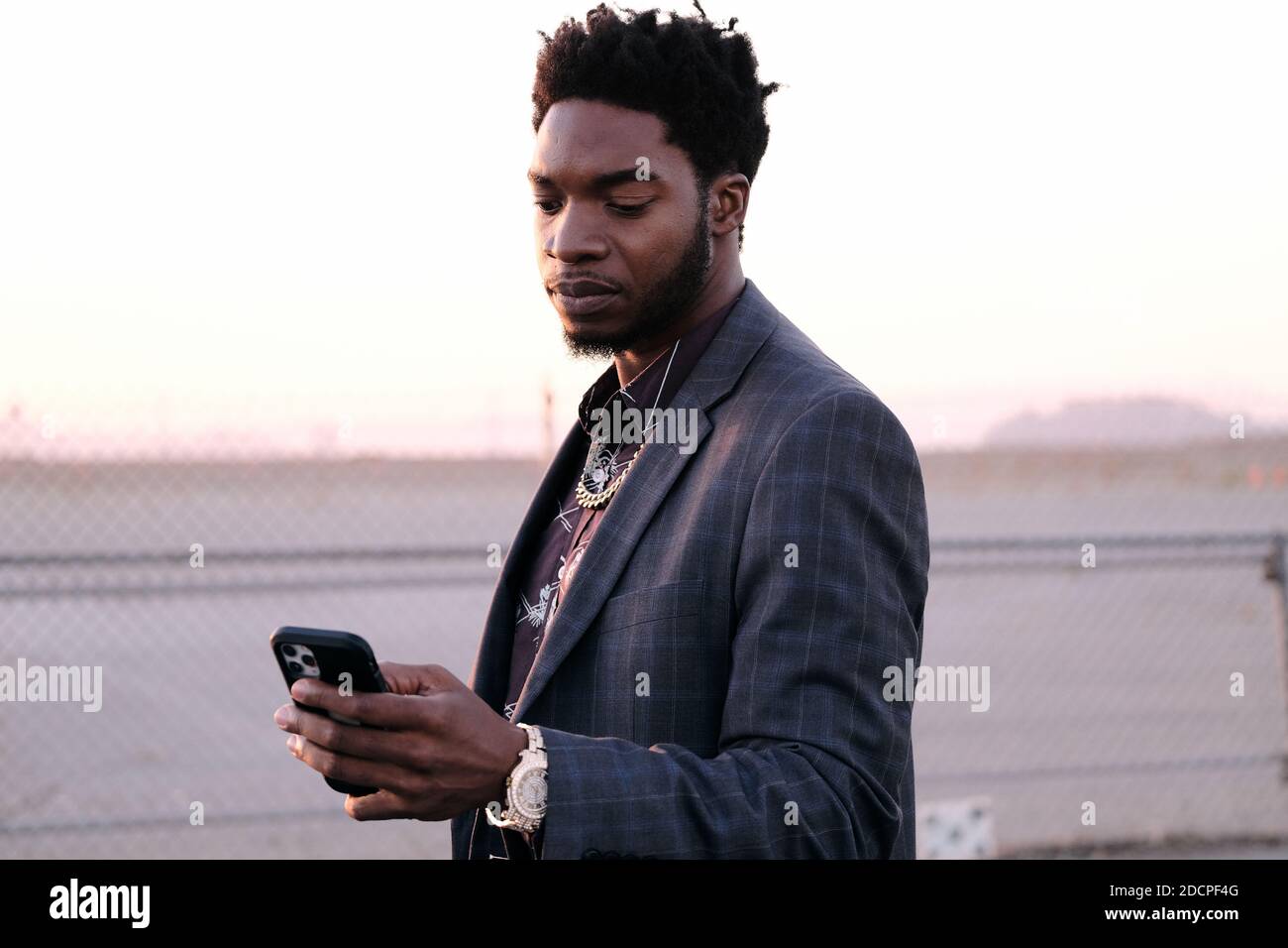 Ein afroamerikanischer Geschäftsmann ruft bei Sonnenuntergang das Telefon ab Stockfoto