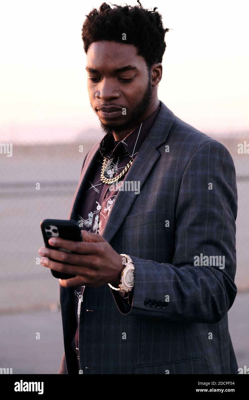 Ein afroamerikanischer Geschäftsmann ruft bei Sonnenuntergang das Telefon ab Stockfoto