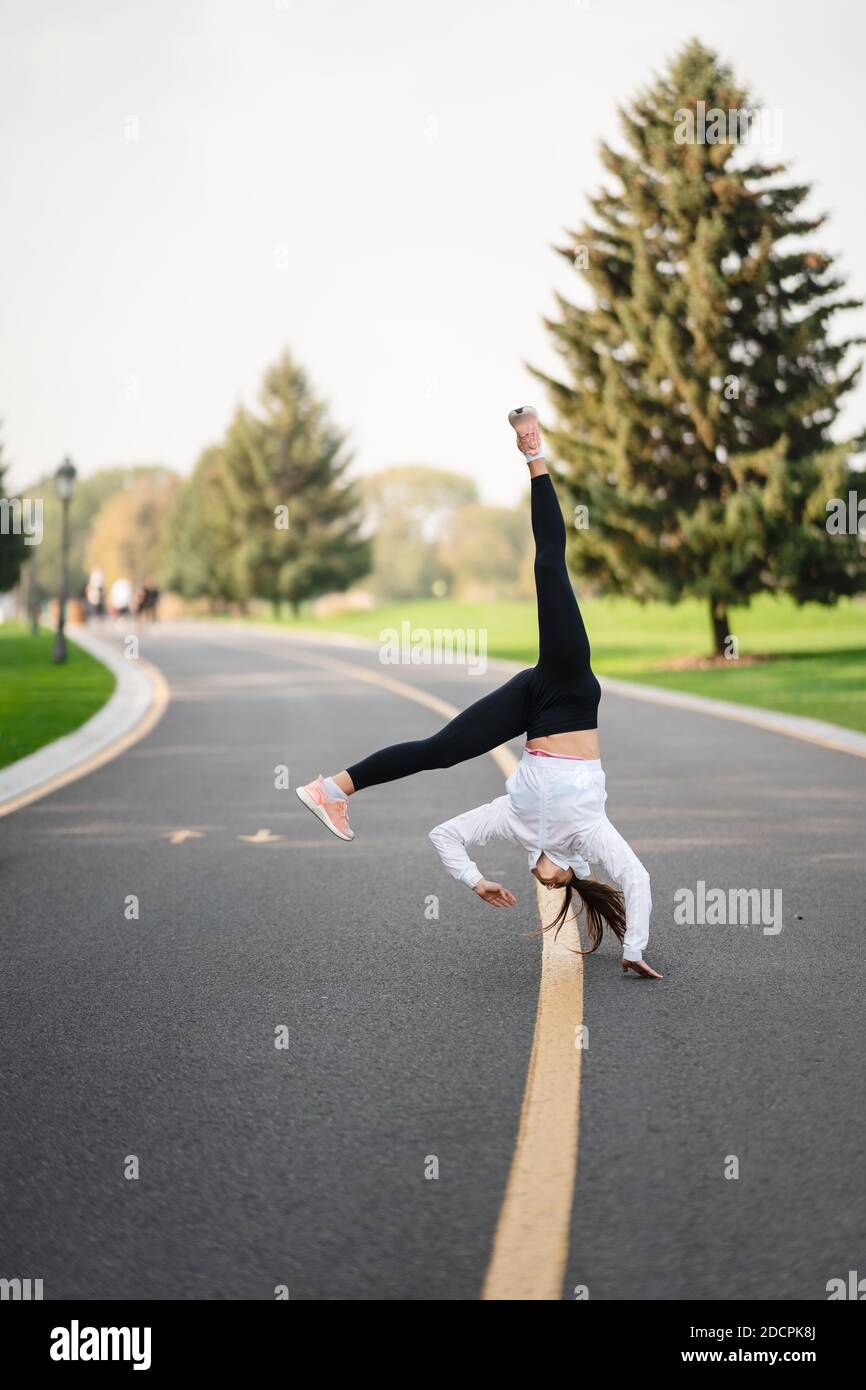 Frau Sportlerin springt auf die Straße und macht Übungen im Freien. Stockfoto