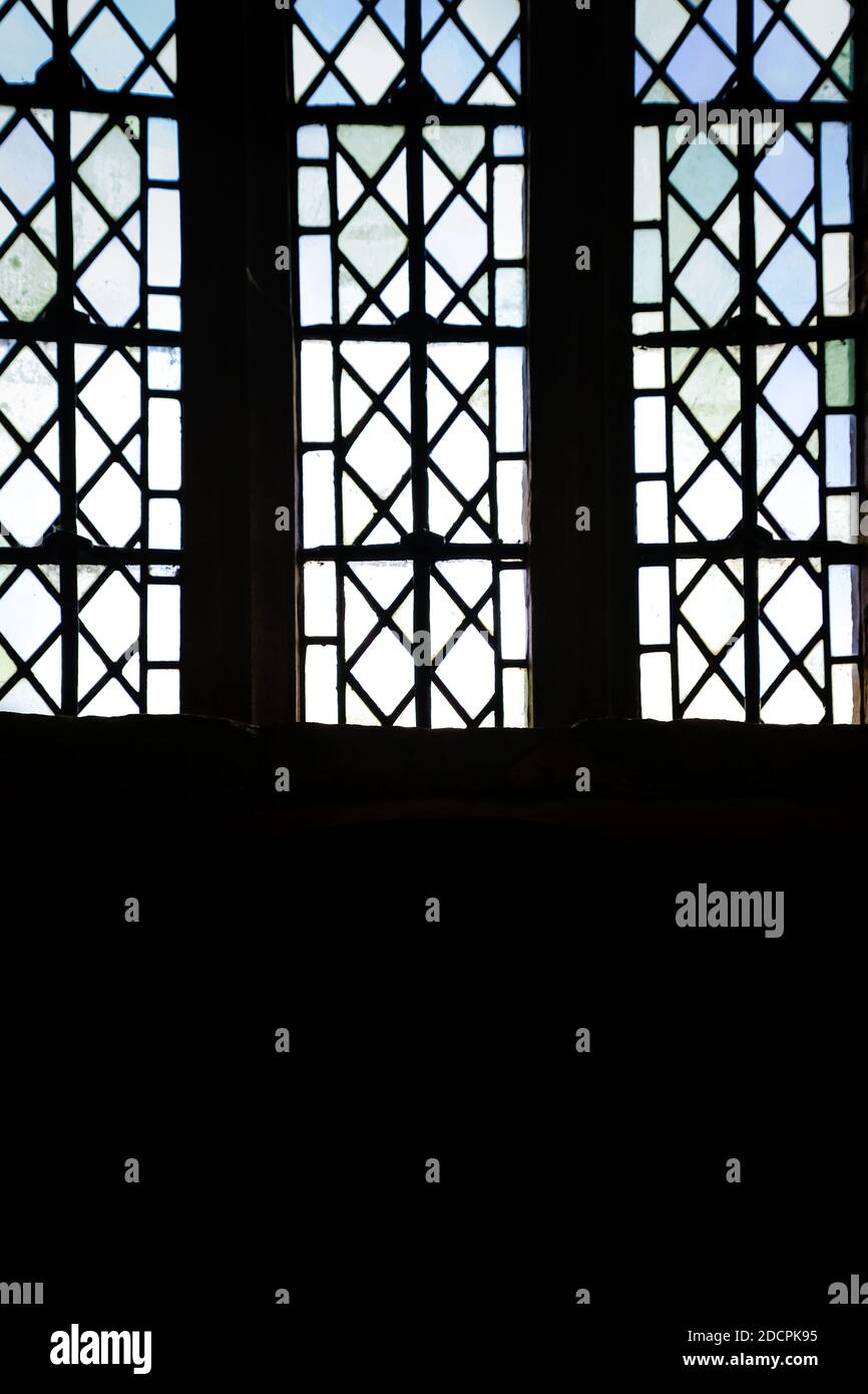 Nahaufnahme von Bleiglasfenstern, die als Silhouetten in der Kirche aus dem 15. Jahrhundert erscheinen, befiehlt Ehrfurcht im Dunkeln Stockfoto