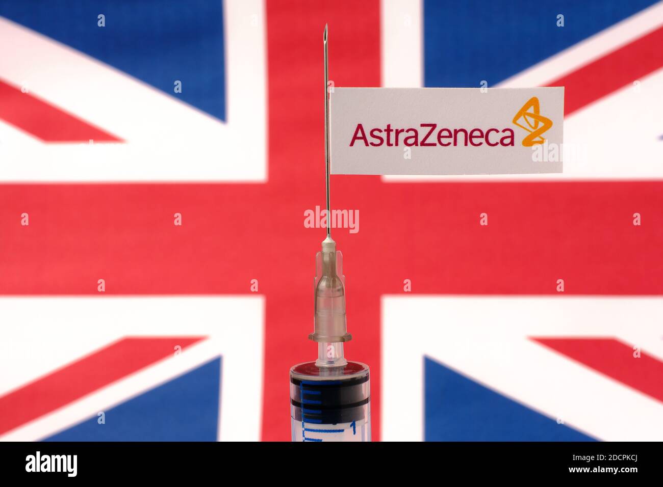 Stafford / Vereinigtes Königreich - November 22 2020: AstraZeneca Oxford Impfstoff Covid-19 Konzept. Spritzennadel und Aufkleber darauf, verschwommene UK-Flagge auf der BA Stockfoto