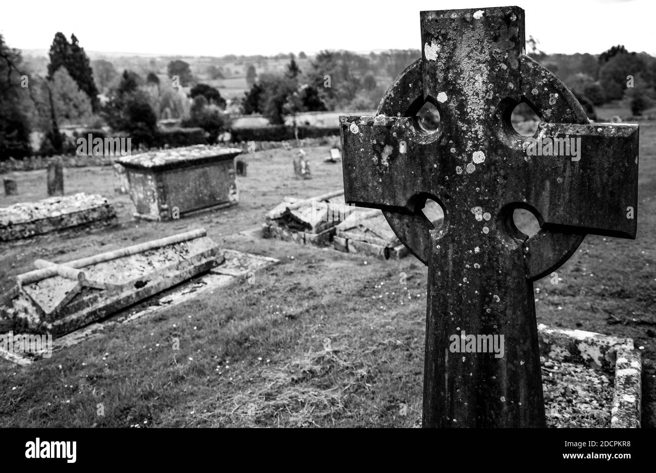 Nahaufnahme eines keltischen Kreuzes in einer Gemeinde der Alten Welt friedhof in St. Michael & All Angels Kirche mit Blick auf ein Hügelige Landschaft der englischen Landschaft Stockfoto