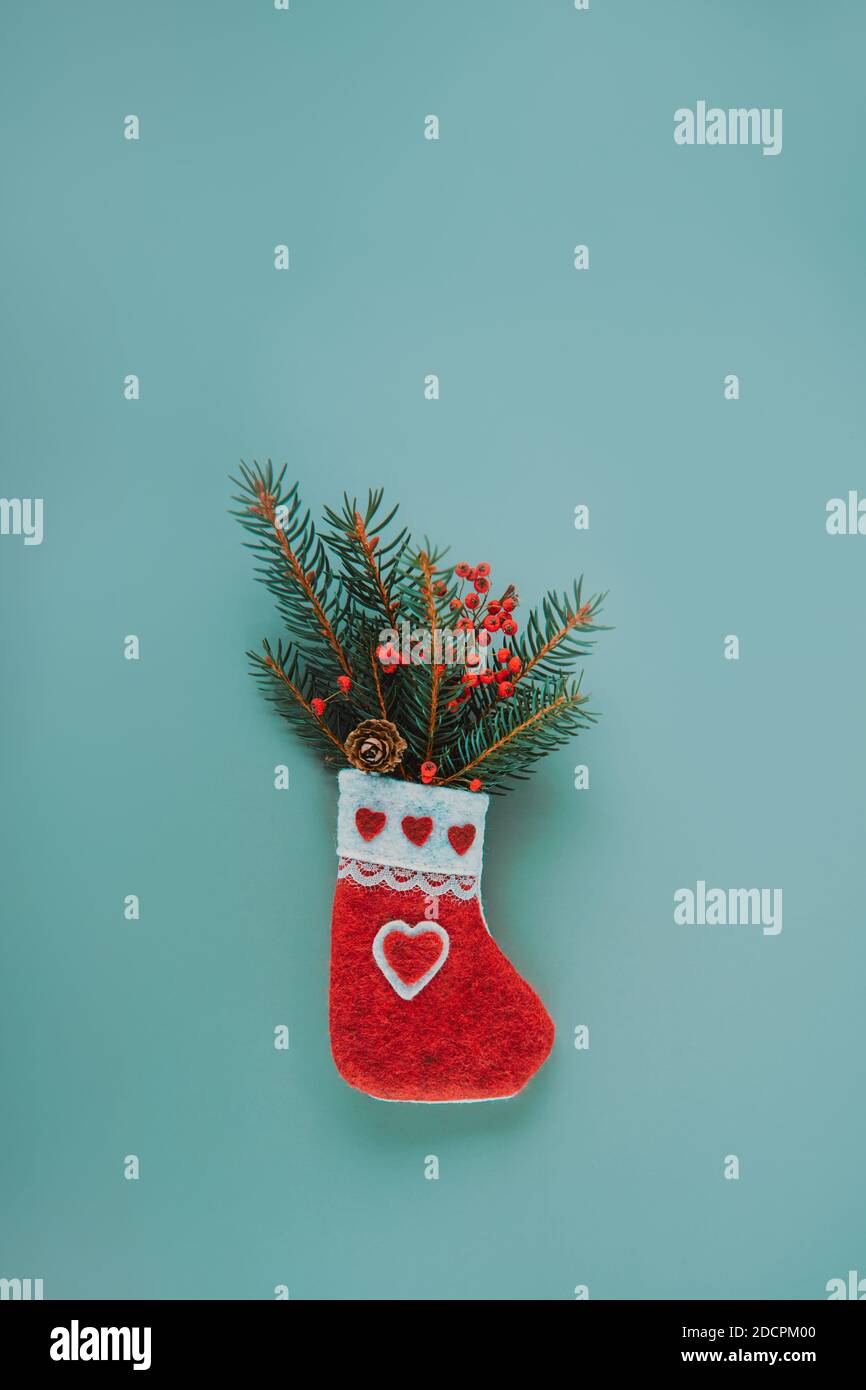 Grußkarte Mockup mit Weihnachten dekorative handgemachte Filzsocke mit Fichtenzweige und trockene Beeren und Kegel auf trendig gedämpft Grüner Hintergrund Stockfoto