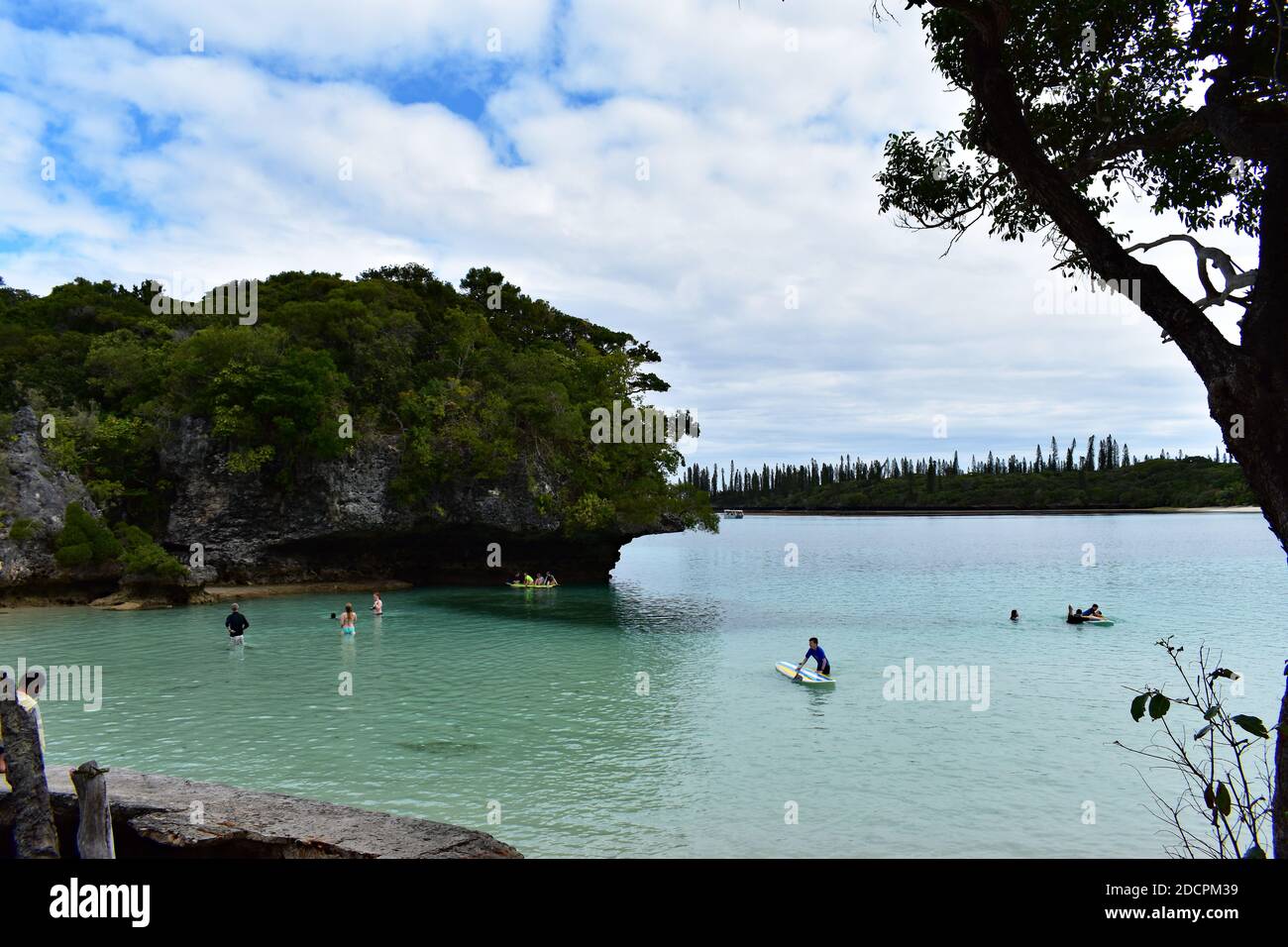 Der heilige Felsen, Rocher de Kaa Nuë Méra in Kanumera Bay auf Isle of Pines, Neukaledonien. Touristen schwimmen im blauen Wasser und spielen auf Paddelbrettern. Stockfoto