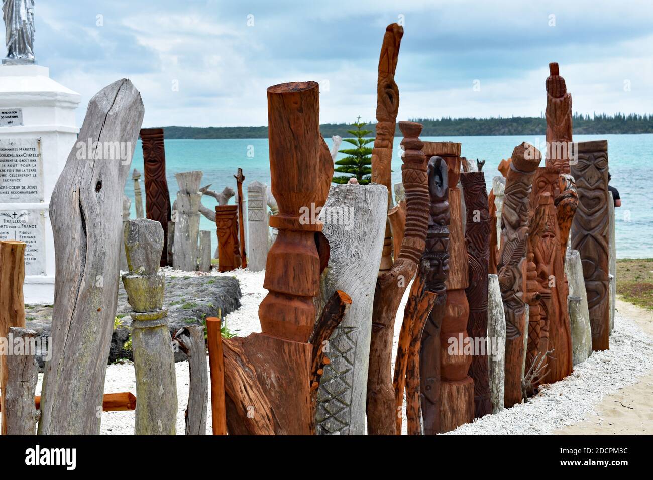 Eine Skulptur von Saint-Maurice wird von einem Zaun ​​of geschnitzten hölzernen Totems in der Bucht von St. Maurice, Vao, Insel Pines, Neukaledonien umgeben. Stockfoto