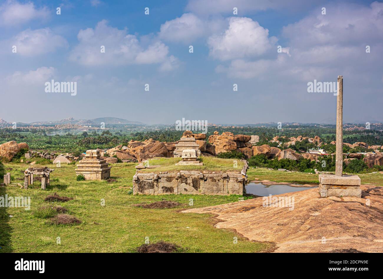 Hampi, Karnataka, Indien - 4. November 2013: Sunset Hill aka Hemakatu. Bergab Tempelruinen und Säule vor dem reichen Ackerland unter Blau Stockfoto