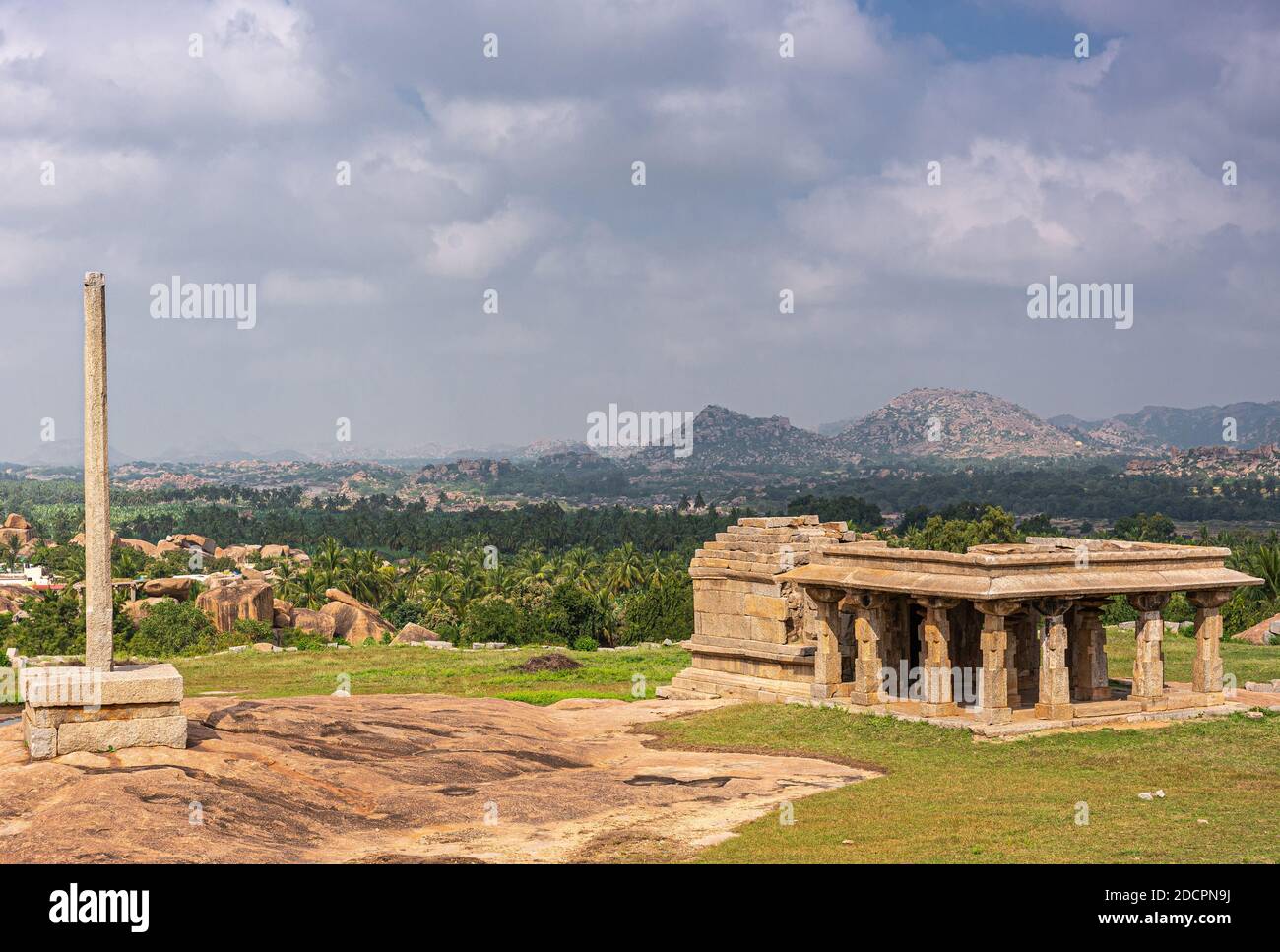 Hampi, Karnataka, Indien - 4. November 2013: Sunset Hill aka Hemakatu. Bergab Tempelruine und Säule vor reichen landwirtschaftlichen Land, felsigen Hügeln Stockfoto