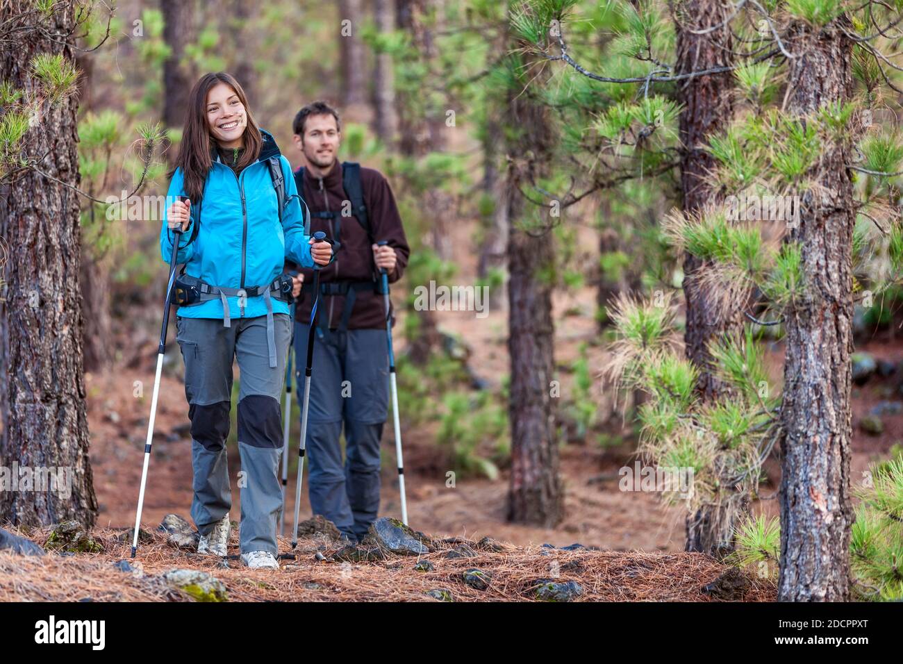 Multirassische Gruppe von Wanderern im Wald. Paar Wandern im Herbst in der Natur im Freien. Asiatische Frau Wanderer vor lächelnd glücklich, Mann zu Fuß hinter. Stockfoto