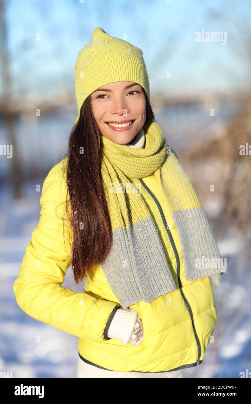 Happy cute asiatische Winter Frau im Schnee tragen gelbe Mode Oberbekleidung Outfit mit Strickwolle Accessoires Hut, Schal und Daunenjacke. Chinesisches Mädchen Stockfoto