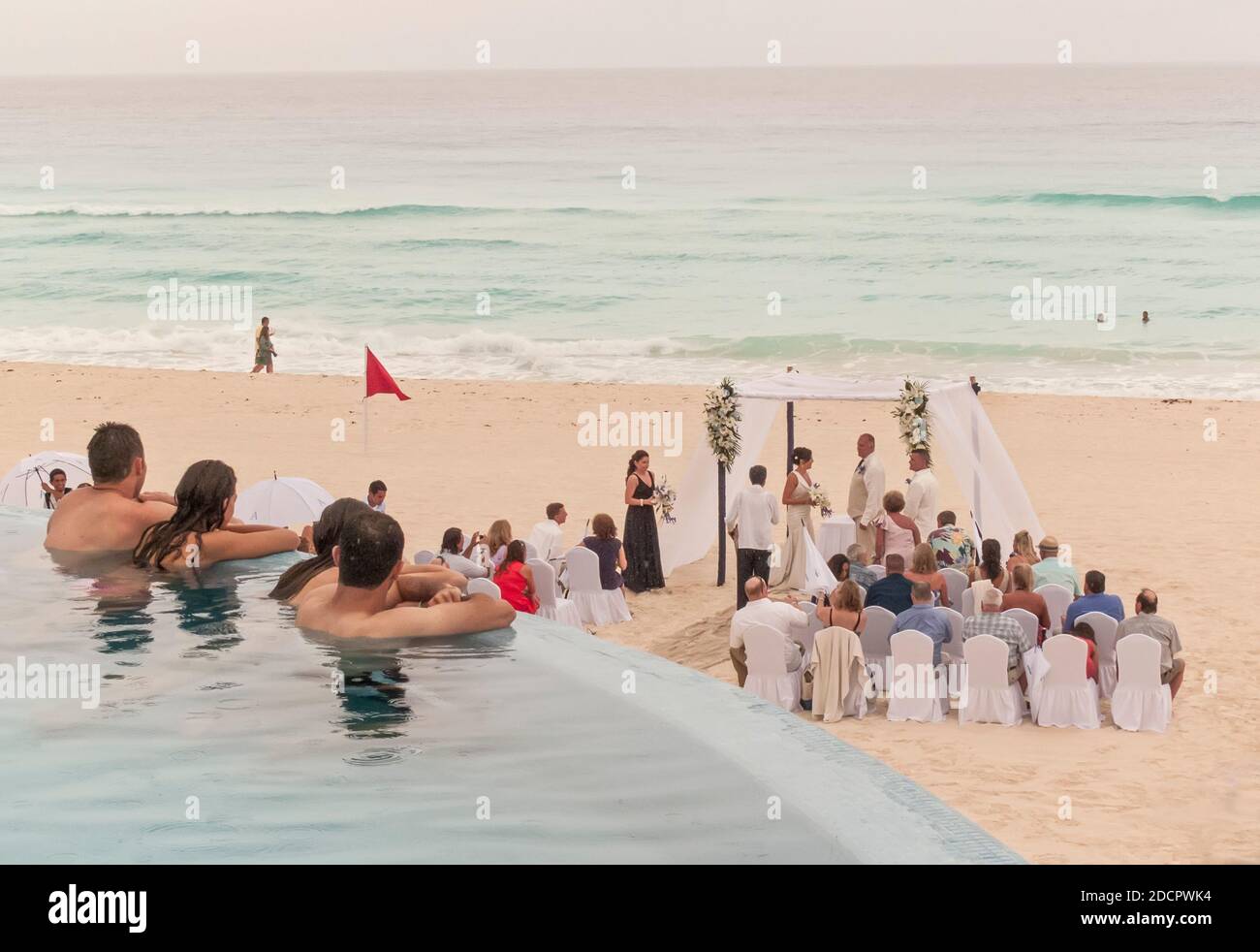 Hotelgäste beobachten eine Strandhochzeit Stockfoto