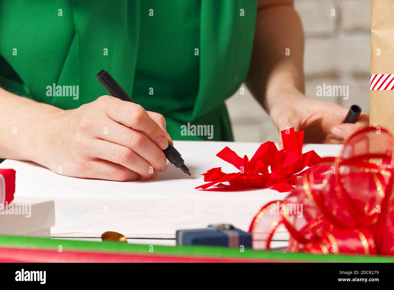 Frau unterzeichnet weihnachtsgeschenke mit einem schwarzen Stift. weihnachtsgeschenke Verpackung Stockfoto