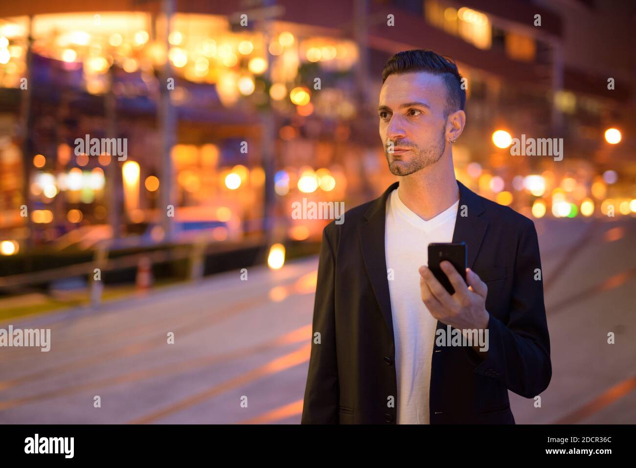 Porträt eines jungen Geschäftsmannes gegen eine Stadt bei Nacht Stockfoto