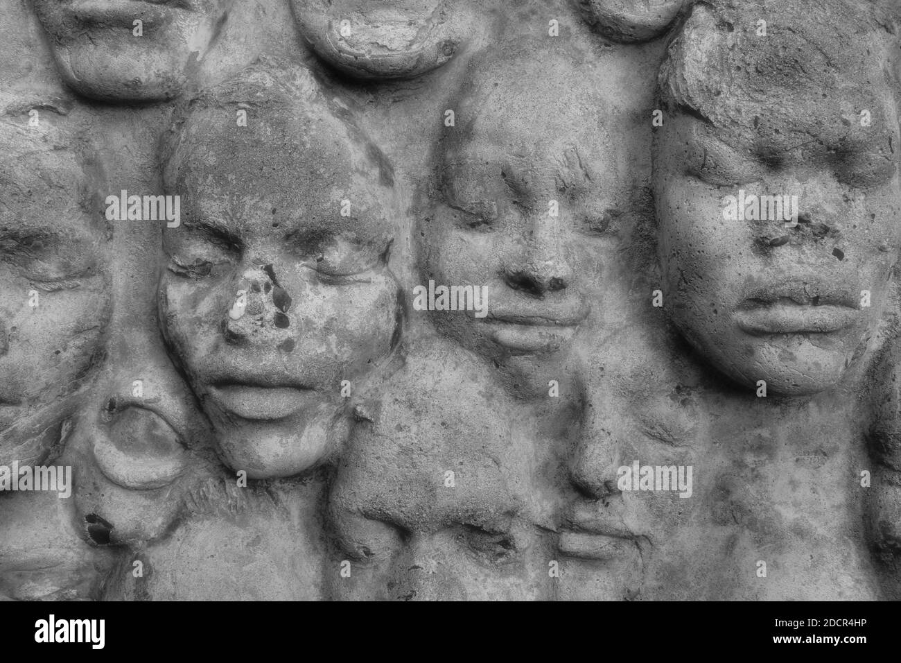 In Zement gegossene Gesichter auf einer verwitterten Wand am City College von San Francisco, Kalifornien; eine Vielzahl von Gesichtern mit geschlossenen Augen. Stockfoto