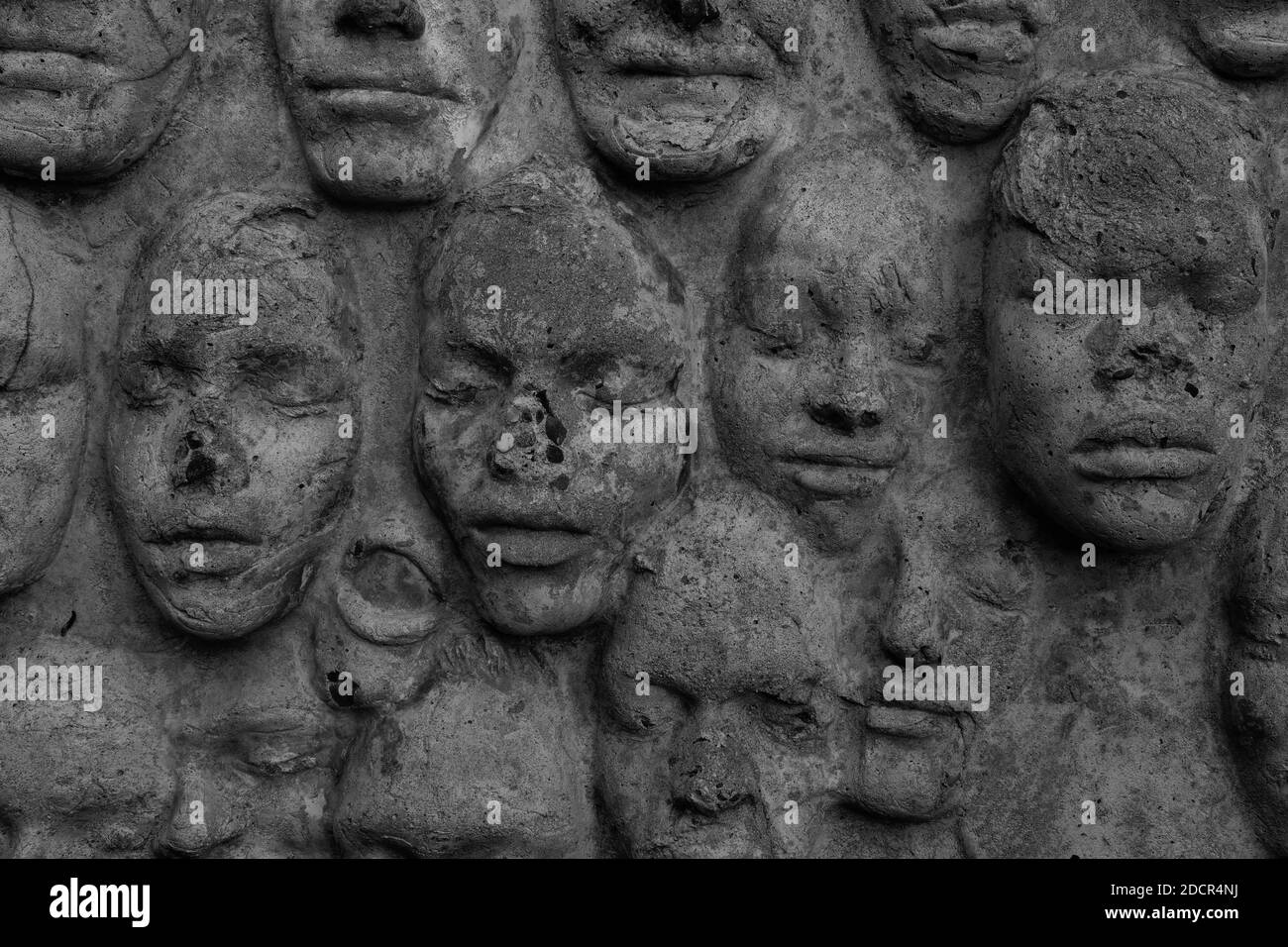 In Zement gegossene Gesichter auf einer verwitterten Wand am City College von San Francisco, Kalifornien; eine Vielzahl von Gesichtern mit geschlossenen Augen. Stockfoto