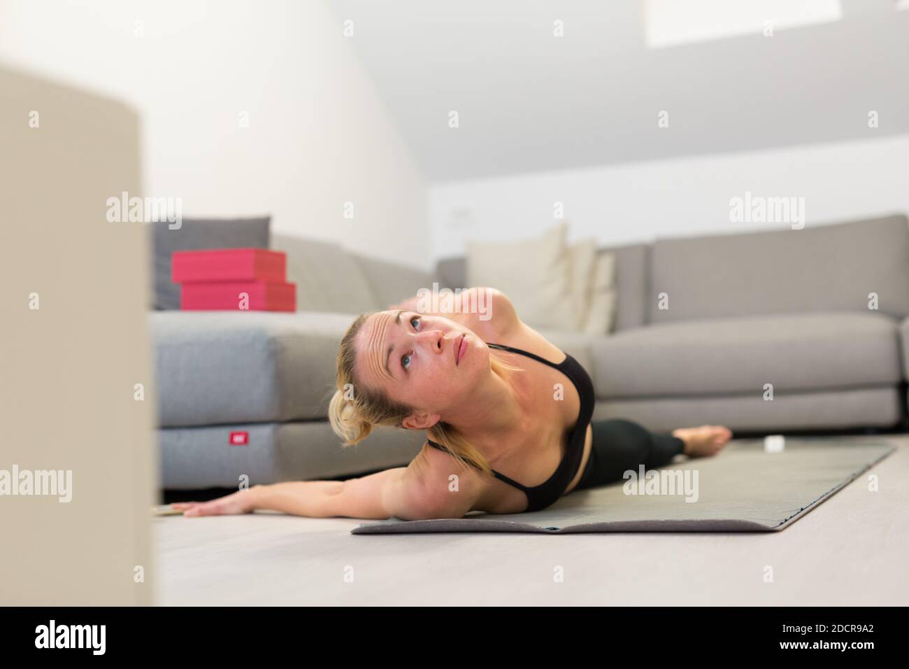 Schöne blonde Frau tun zu Hause Training drinnen. Frau praktiziert Yoga zu Hause. Fit Mädchen mit Workout-Tutorials für einen gesunden aktiven Lebensstil. Frau Stockfoto
