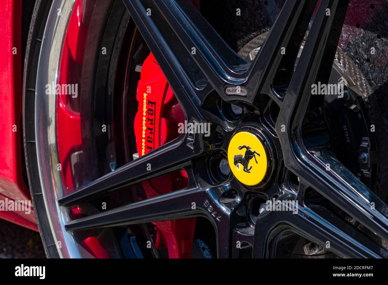 Detail eines roten Ferrari-Autos mit dem roten Bremssattel, Teil der Felge mit dem Cavallino Rampante, einem schwarzen Stechhengst auf gelbem Schild. Stockfoto