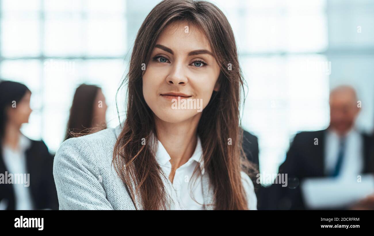 Junge Geschäftsfrau vor dem Hintergrund ihrer Kollegen. Stockfoto