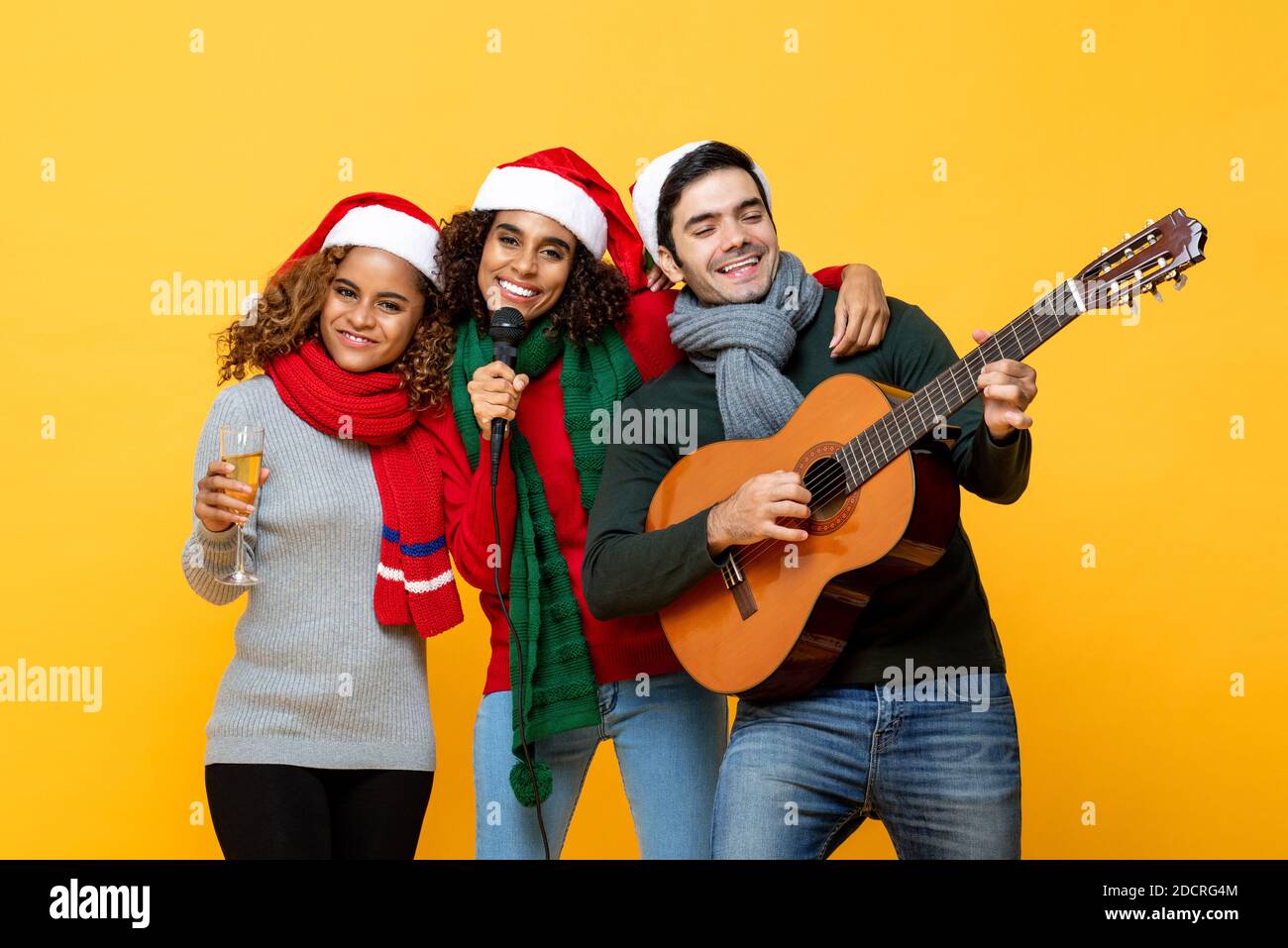 Portrait von verschiedenen Freunden, die Party singen trinken und feiern Weihnachten auf gelbem isoliertem Hintergrund Stockfoto