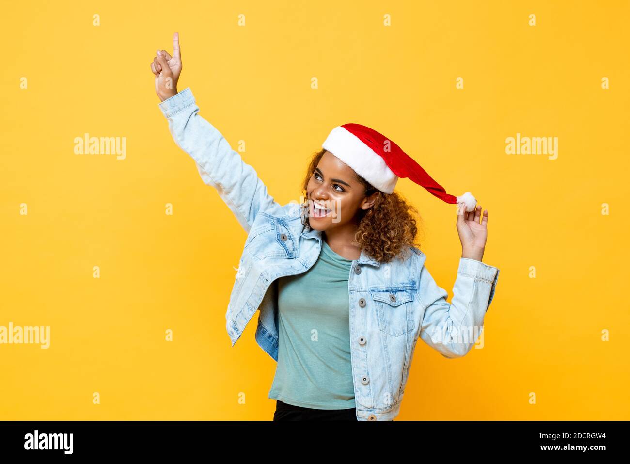 Spaß überrascht glücklich afroamerikanische Frau trägt Weihnachtsmütze poiting Hand auf gelbem, isoliertem Hintergrund Stockfoto