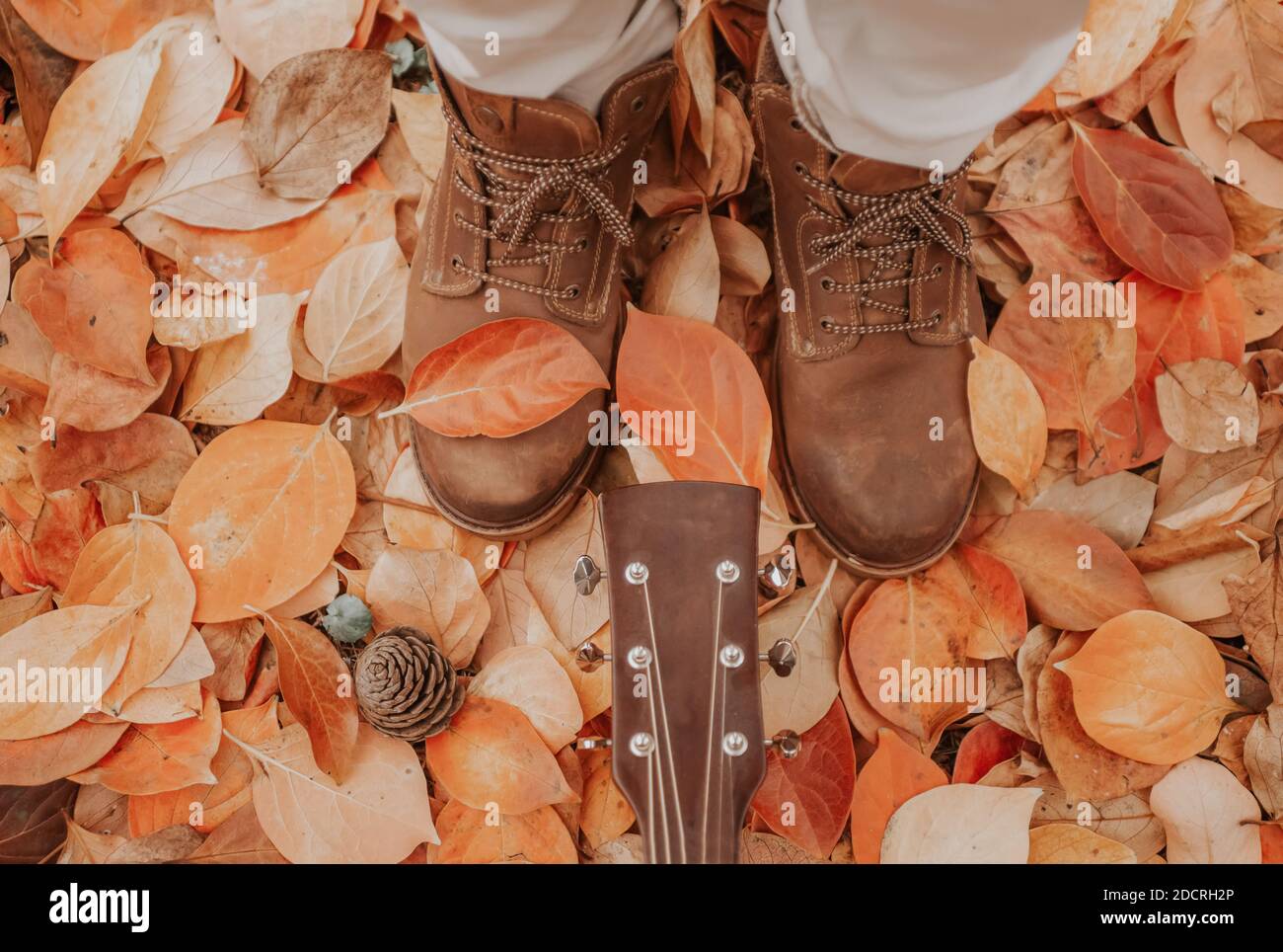 Unerkennbares Nahaufnahme Porträt auf Mann Schuhe und seine Gitarre Auf dem Boden mit Boden in fallenden orange foliage.autumn bedeckt Lifestyle-Konzept für Stimmung Stockfoto
