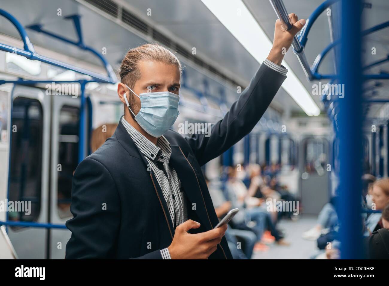 Junger Mann in einer Schutzmaske, der in einem U-Bahn-Auto steht. Stockfoto