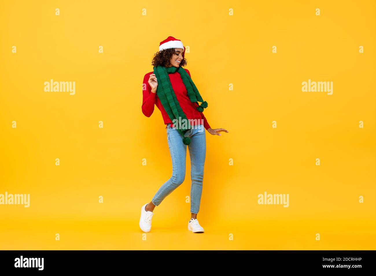 Fun Porträt von glücklichen afroamerikanischen Frau in Weihnachten Kleidung tanzen auf isoliertem gelben Studiohintergrund Stockfoto