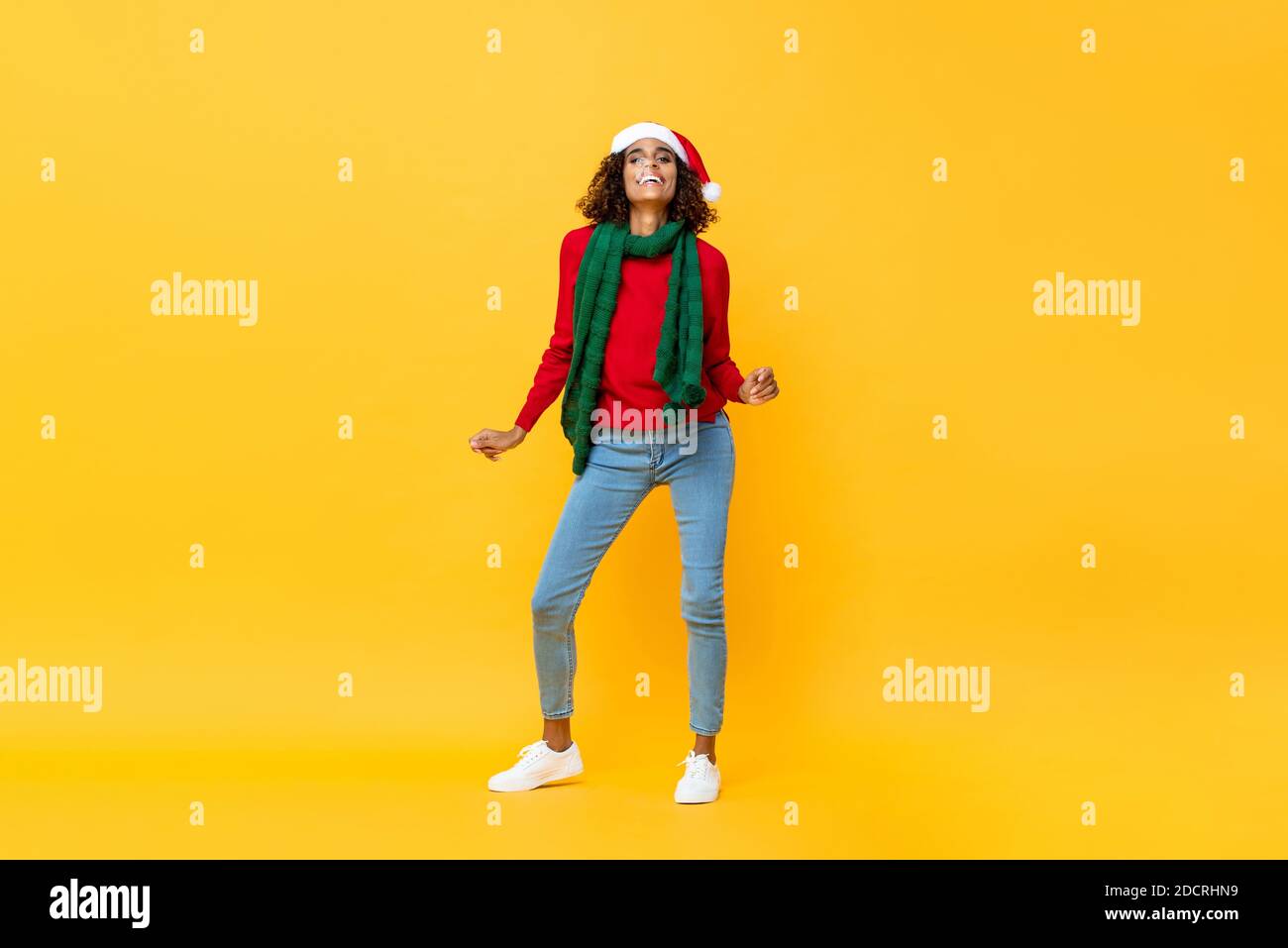 Fun Porträt von glücklichen afroamerikanischen Frau in Weihnachten Kleidung tanzen auf isoliertem gelben Studiohintergrund Stockfoto