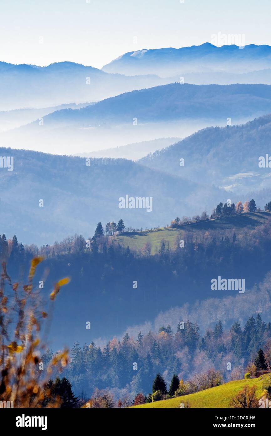 Schöne Aussicht auf neblige Täler, Wälder und Hügel im Herbst von hoher Position in Slowenien. Tourismus, Wandern, Natur, Umwelt und Forstwirtschaft Konzept Stockfoto