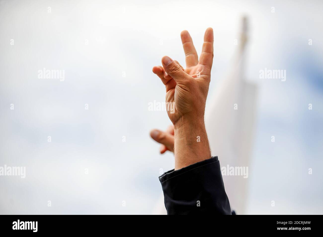 Details mit der Hand eines Protestierenden, der das Siegeszeichen während einer politischen Kundgebung zeigt. Stockfoto