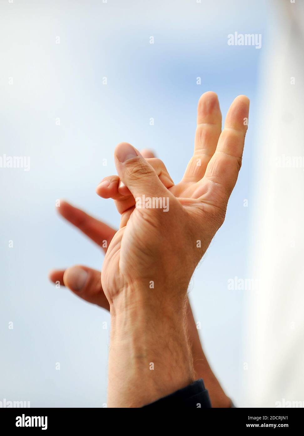 Details mit der Hand eines Protestierenden, der das Siegeszeichen während einer politischen Kundgebung zeigt. Stockfoto