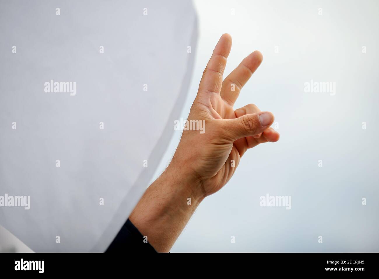 Details mit der Hand eines Protestierenden, der das Siegeszeichen während einer politischen Kundgebung zeigt. Stockfoto