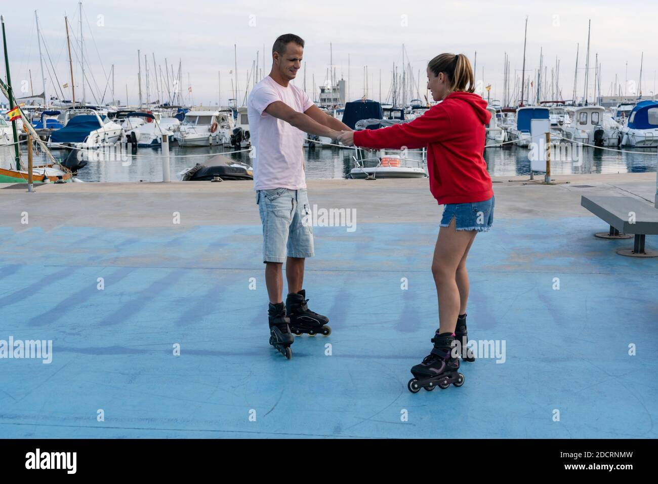 Junge schöne paar Rollschuh im Skatepark neben dem erstaunlichen Hafen im Sommer.Freundschaftssport und gesunde Lifestyle-Konzept. Stockfoto