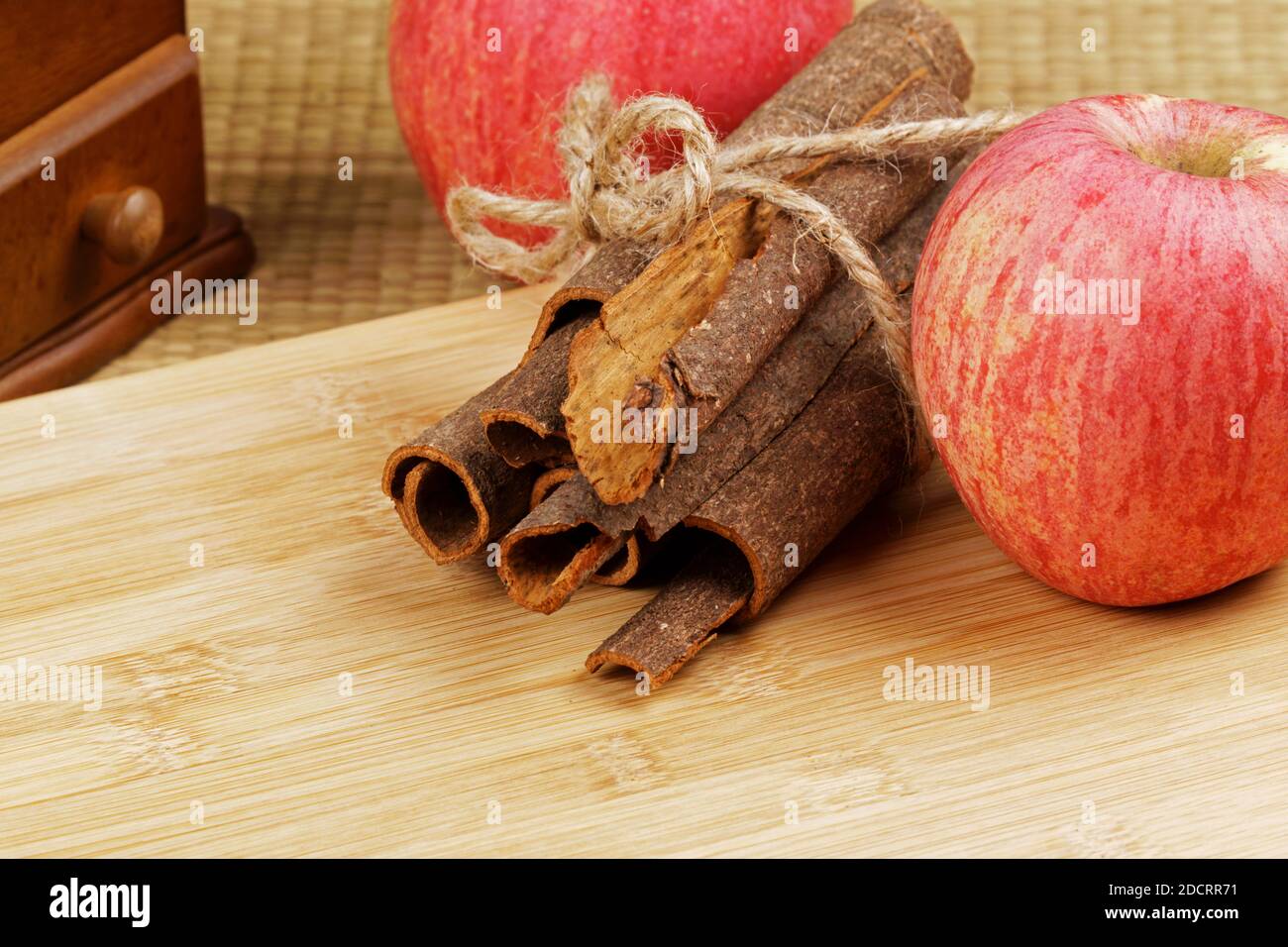 Köstliche Zimtrinde und rote Äpfel auf einem hölzernen Hintergrund Stockfoto
