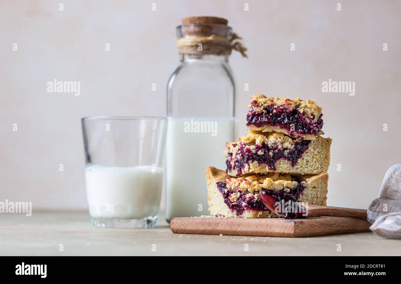 Hausgemachte Beeren Marmelade Mürbeteig Quadrate und Glas Milch, hellen Beton Hintergrund. Selektiver Fokus. Stockfoto