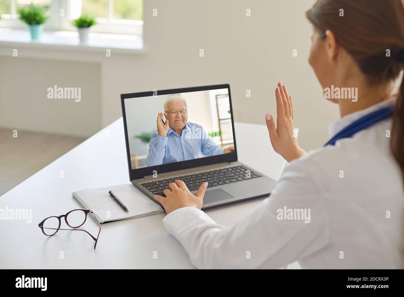 Lächelnd älteren Mann Patient Gruß professionelle Frau Arzt online Während eines entfernten Meetings Stockfoto