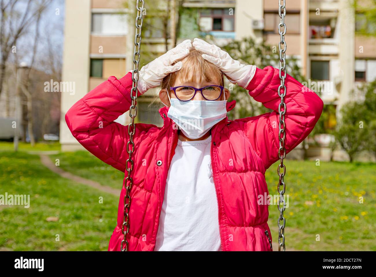 Kleines Mädchen in medizinischer Maske und Handschuhen schwingt allein gestikulierende Sorge über Virus COVID-19, Corona. Stockfoto